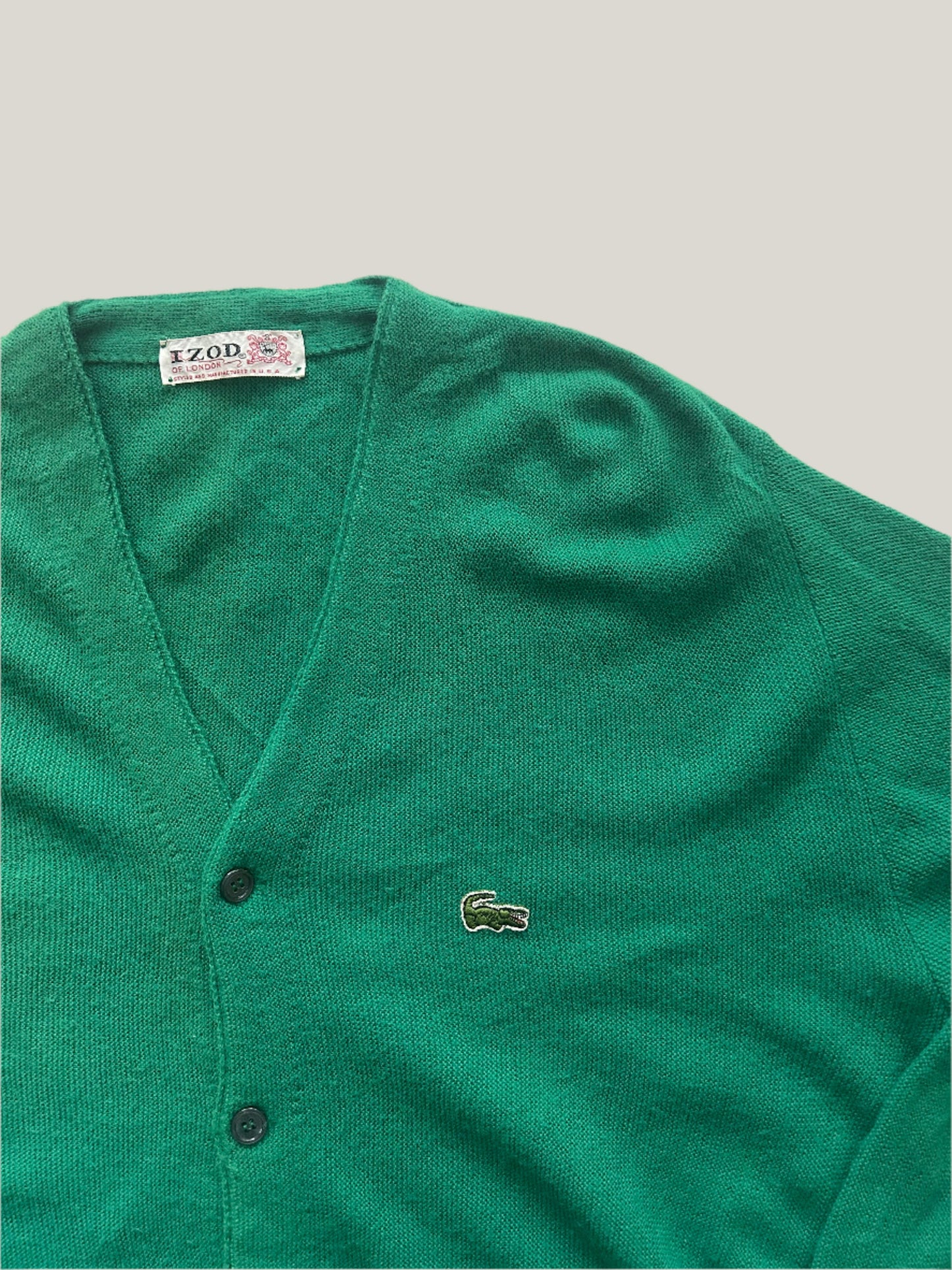 Green vintage Lacoste cardigan on a light gray background