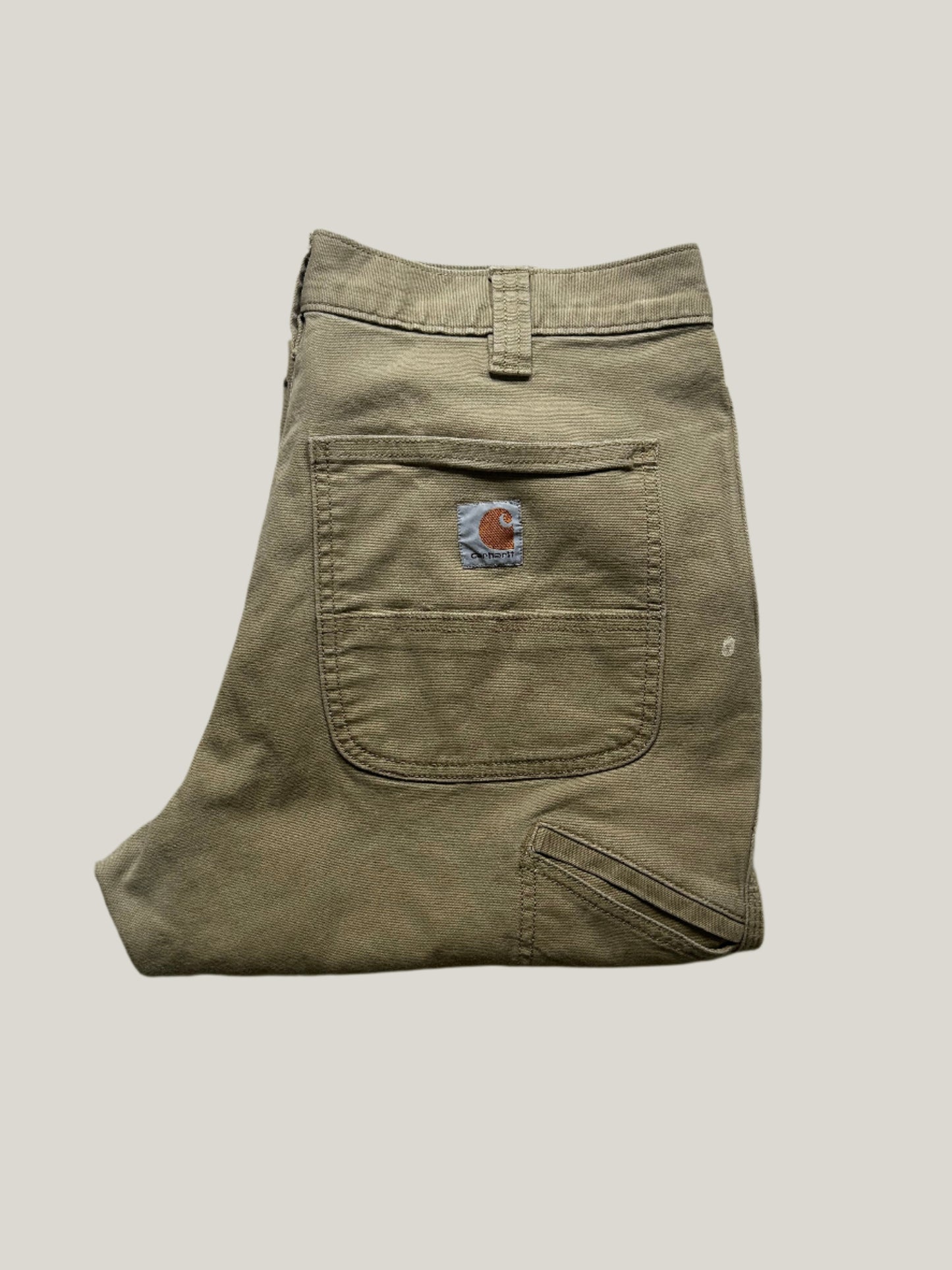 Khaki carhartt pants with a carhartt logo on a back pocket
