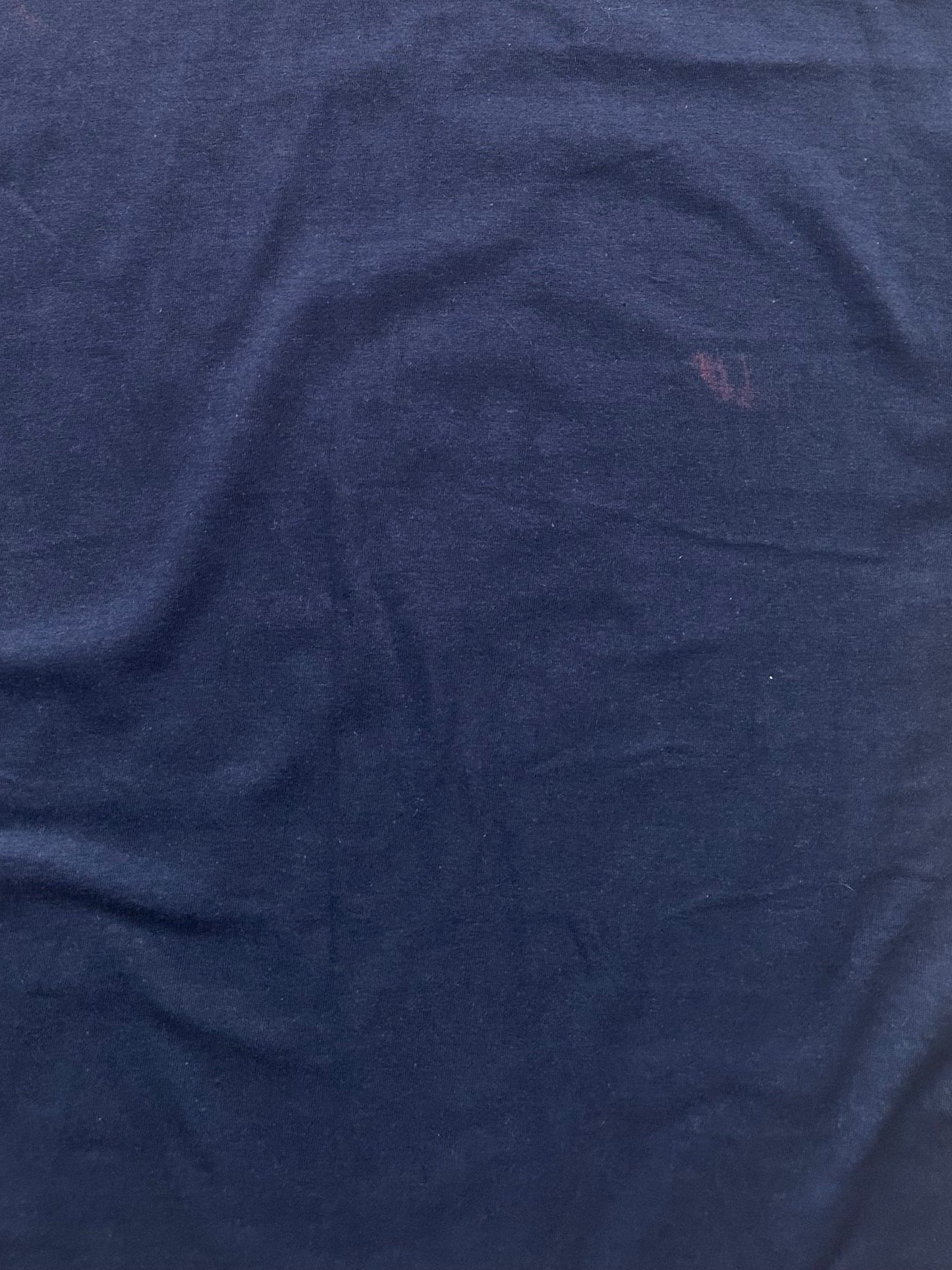 Light purple stain on the backside of the dark blue t-shirt