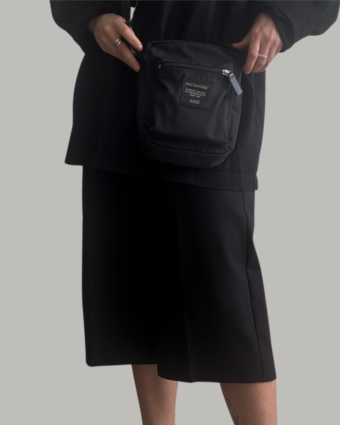 Person holding a black marimekko x ratia cash & carry bag against a plain background