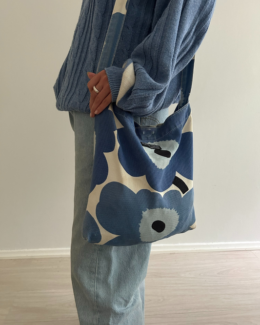 Person holding a blue marimekko unikko bag  against a plain background