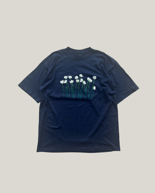 Dark blue T-shirt with a design of white tulip-like flowers and green stems arranged across the chest.