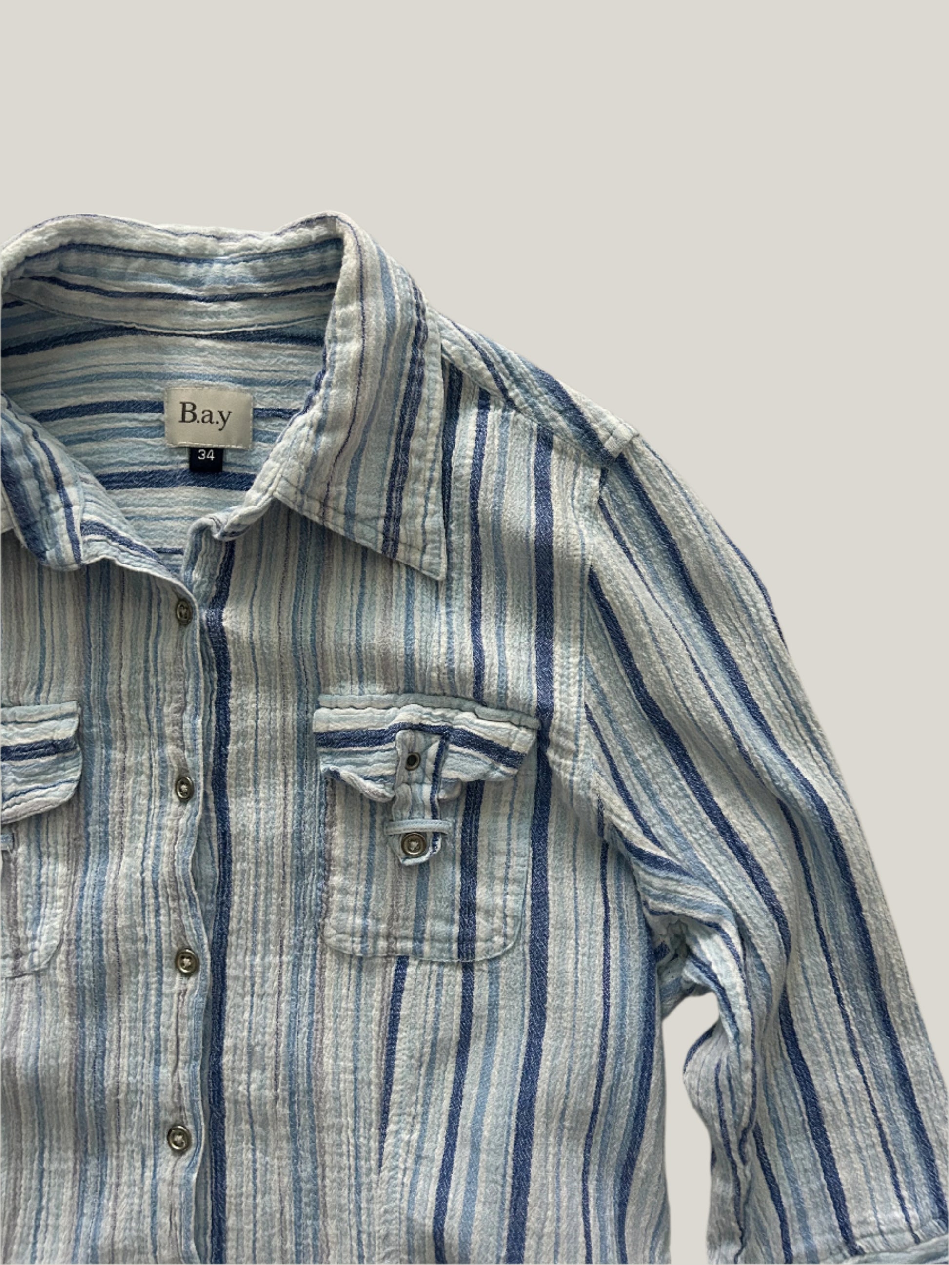 close up of womens striped button-up shirt in different shades of blue with two chest pockets and 3/4 sleeves and collars
